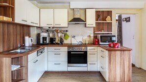 Una cocina moderna con armarios blancos, horno empotrado, microondas y encimeras de madera.