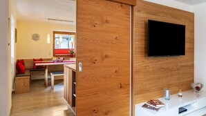 Una sala de estar moderna con un panel de pared de madera, un televisor de pantalla plana y un comedor al fondo.