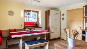 Cocina compacta con una mesa de madera, banco y ventana con persianas rojas.