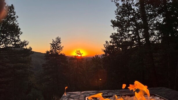 Une terrasse dotée d’un foyer extérieur et offrant une vue sur le coucher de soleil.