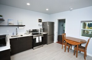 A modern kitchen with dark cabinets, stainless steel appliances, and a wooden dining table. - Walk to the beach in minutes from this recently remodeled condo. (Nokomis)