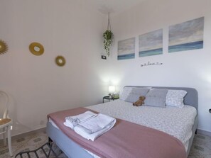 A bedroom with a bed, a chair, and wall art including sun motifs and a 'love' sign.