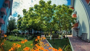 A courtyard with a pathway, trees, and orange flowers. - Studio - Sleeps 4 & Access to Pools (Bourgas)