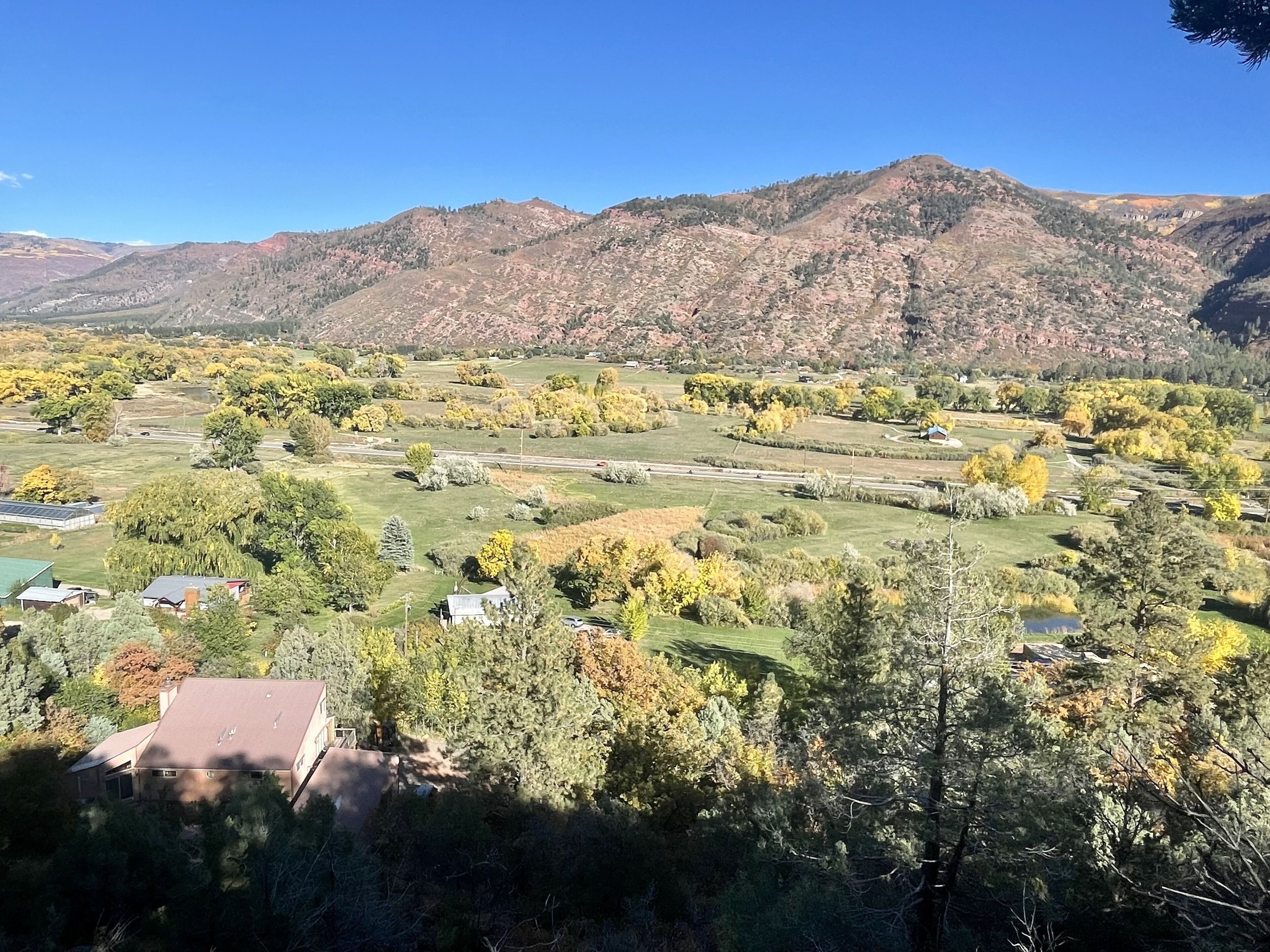 A rural landscape with rolling hills, scattered houses, and a clear blue sky.