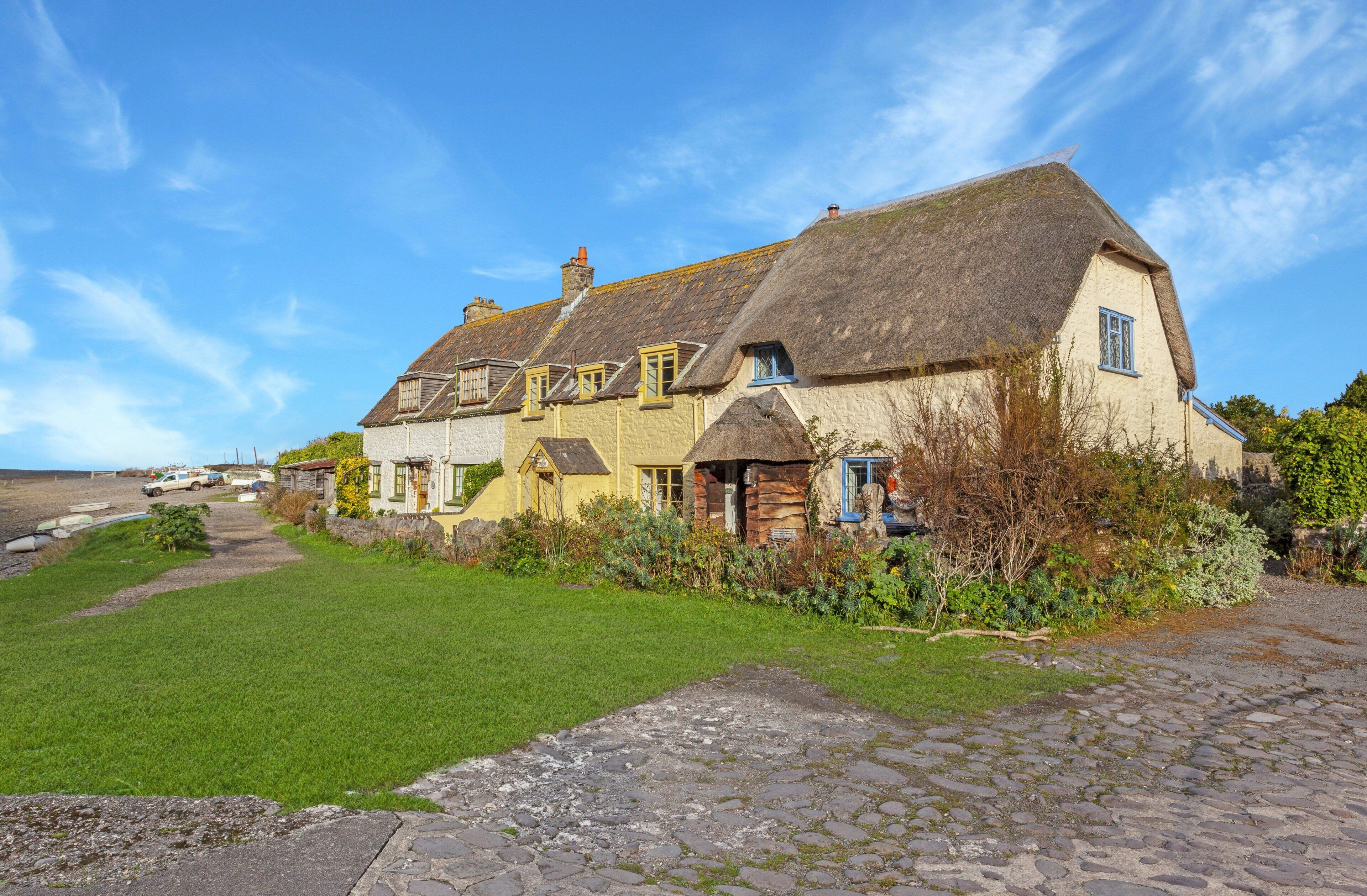 A traditional thatched-roof house with a stone pathway leading to the entrance.