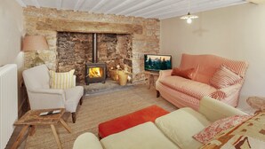 A cozy room with a stone fireplace, striped sofas, and a television.