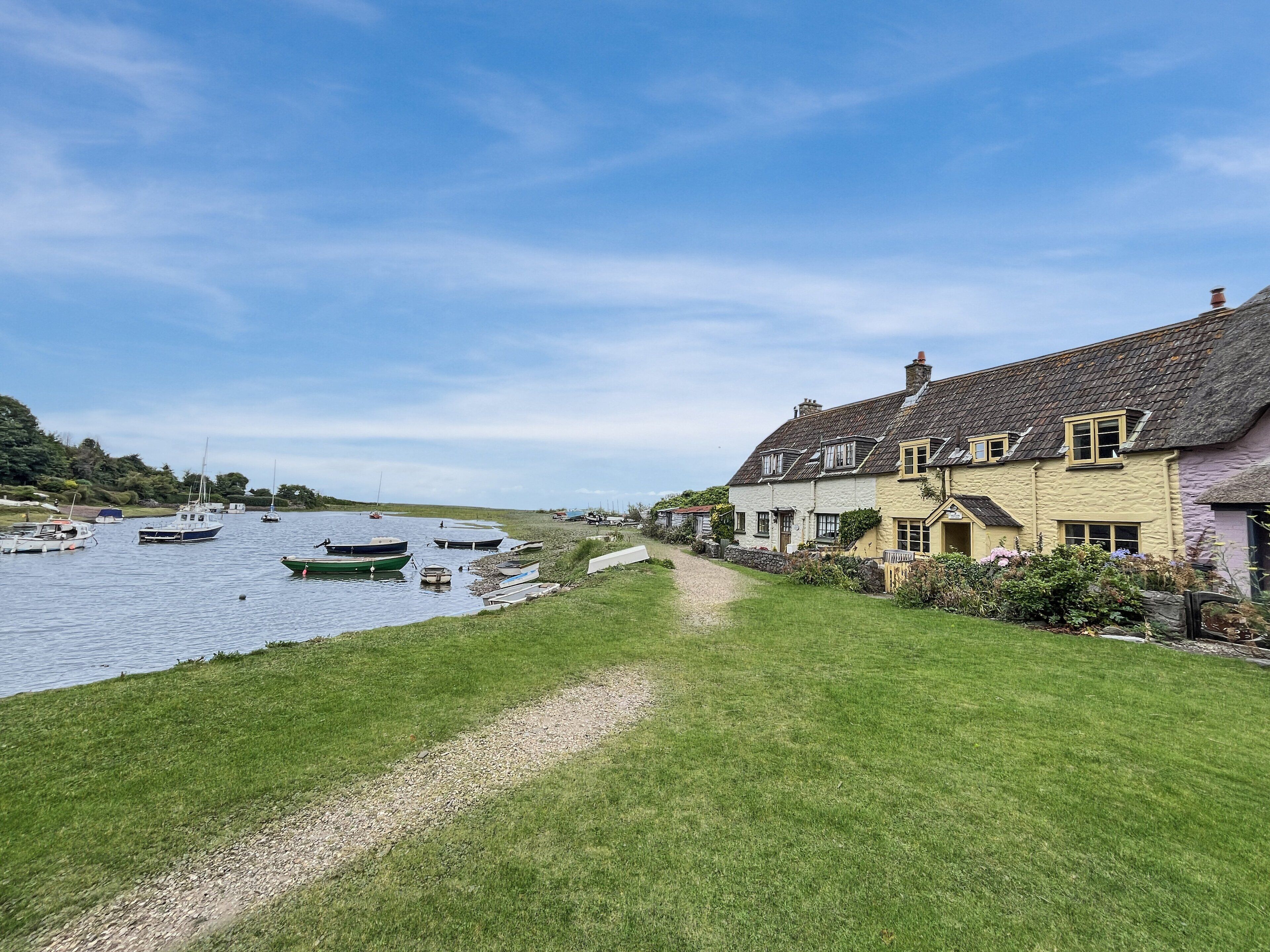 A riverside pathway leading to traditional houses with a river view.