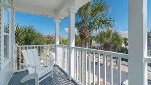 Un porche couvert avec des balustrades blanches et une seule chaise blanche.