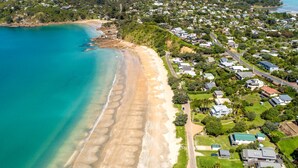 Vista aerea di una zona residenziale costiera con case, una spiaggia e un mare azzurro e limpido.