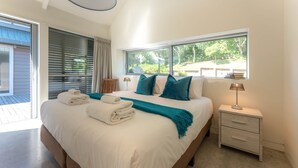Una camera da letto moderna con un letto grande, un comodino con una lampada e una finestra vista verde.
