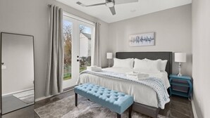 Ein Schlafzimmer mit Bett, einer Sitzbank, einem Deckenventilator und Blick ins Freie.