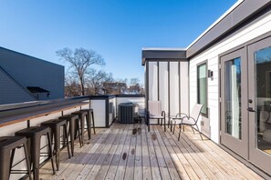 A deck with wooden flooring, metal bar stools, and a glass door leading to a room. - Myrtle One ~ This is a combined listing made of two adjoining 4BR/4BA Condos with adjoining rooftops (Nashville)