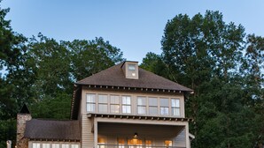 Ein zweistöckiges Haus mit Balkon, einem Stein-Schornstein und einem Steg, der über ein Gewässer führt.