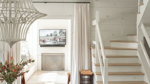 Ein modernes Wohnzimmer mit einer Holztreppe, einem Kamin und einer Essecke mit einem Holztisch und Stühlen.