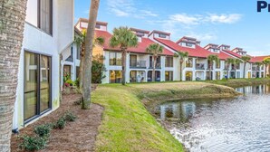 A row of white buildings with red roofs and a calm water body in front.