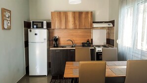 A compact kitchen with a refrigerator, microwave, coffee maker, sink, and stove. - Kerkini Houses (Sintiki)
