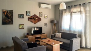 A living room with a sofa, a coffee table, a TV, and artwork on the walls. - Kerkini Houses (Sintiki)