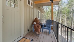 A wooden deck with a blue chair and a person in a furry costume. - PNW ~ Bayview Bigfoot steps to Lake Pend Oreille/Hot Tub (Bayview)