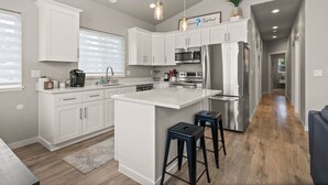 A modern kitchen with white cabinetry, stainless steel appliances, and a central island. - PNW ~ Bayview Bigfoot steps to Lake Pend Oreille/Hot Tub (Bayview)