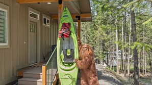 A wooden staircase leading to a porch with a green kayak and life jacket hanging on the railing. - PNW ~ Bayview Bigfoot steps to Lake Pend Oreille/Hot Tub (Bayview)