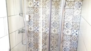 Eine Duschkabine mit Glastür, gefliesten Wänden und einer Badewanne.
