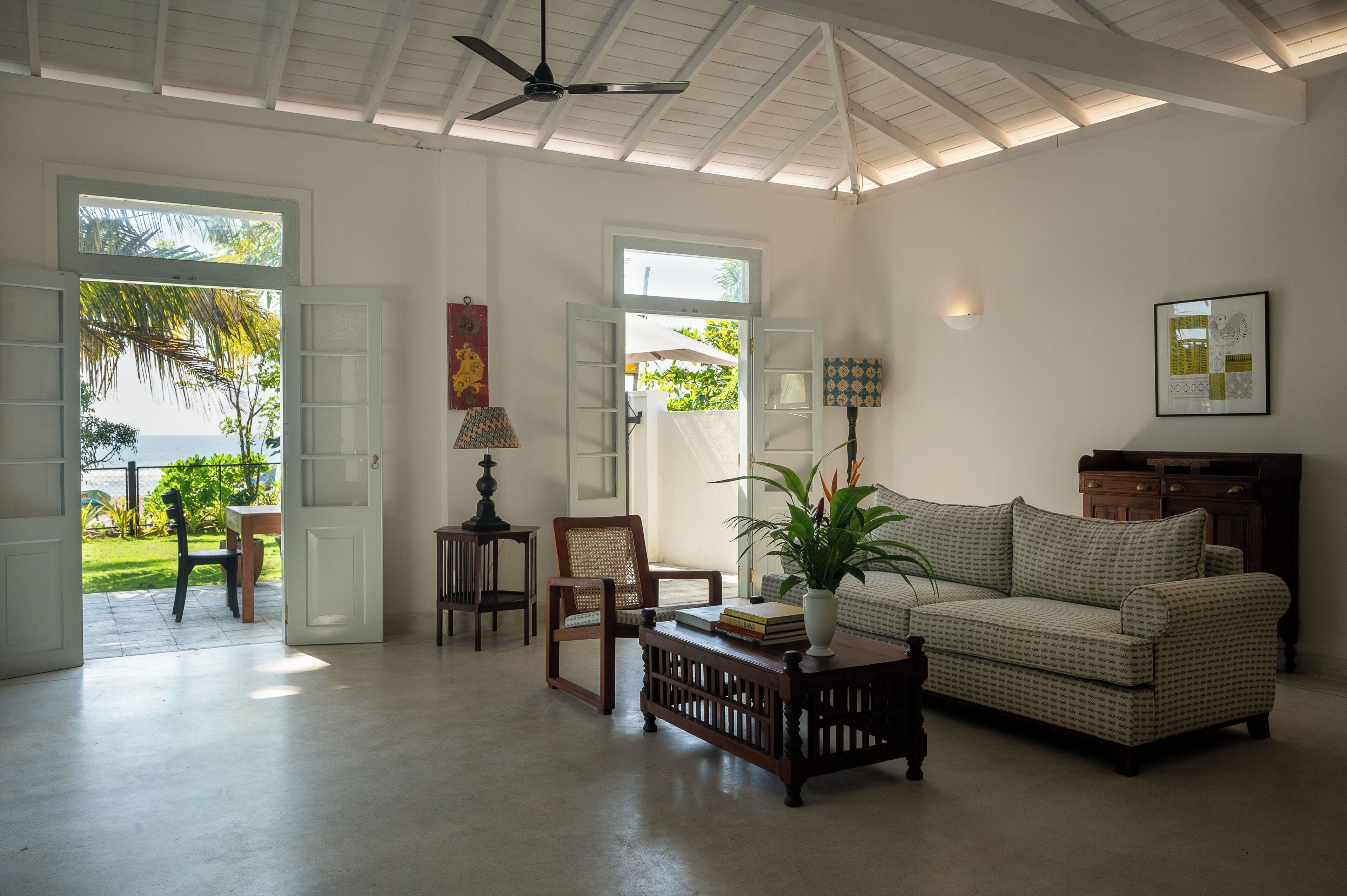 A spacious living room with a view of the sea, a ceiling fan, and a sofa.