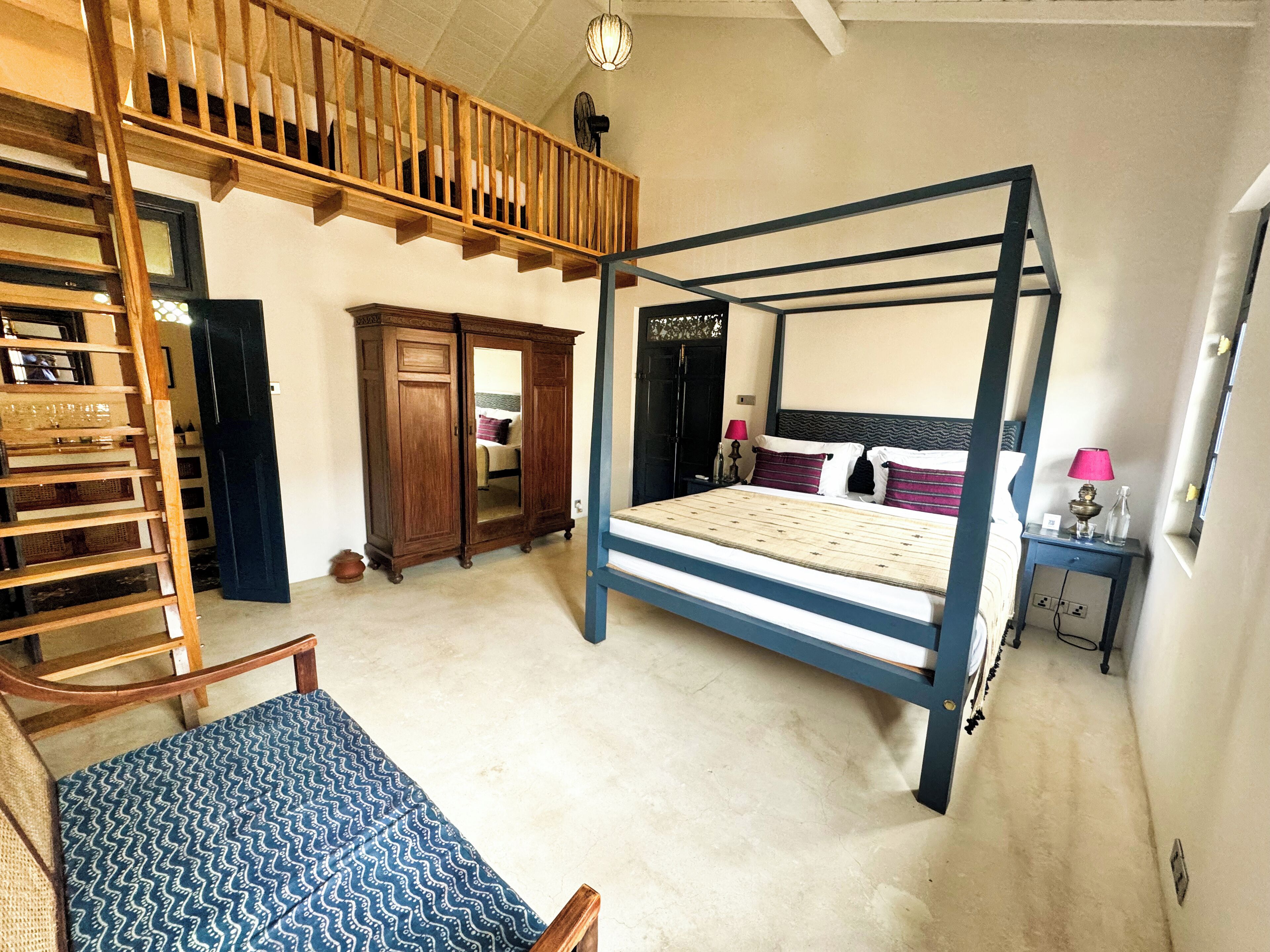 Une chambre à coucher avec un lit à baldaquin, un escalier en bois, une armoire et une table de chevet avec une lampe.
