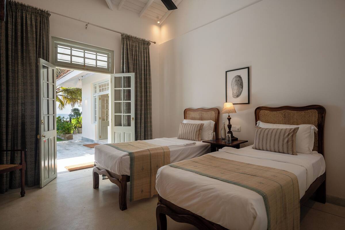A hotel room with two beds, a door leading to an outdoor area, and a framed picture on the wall.