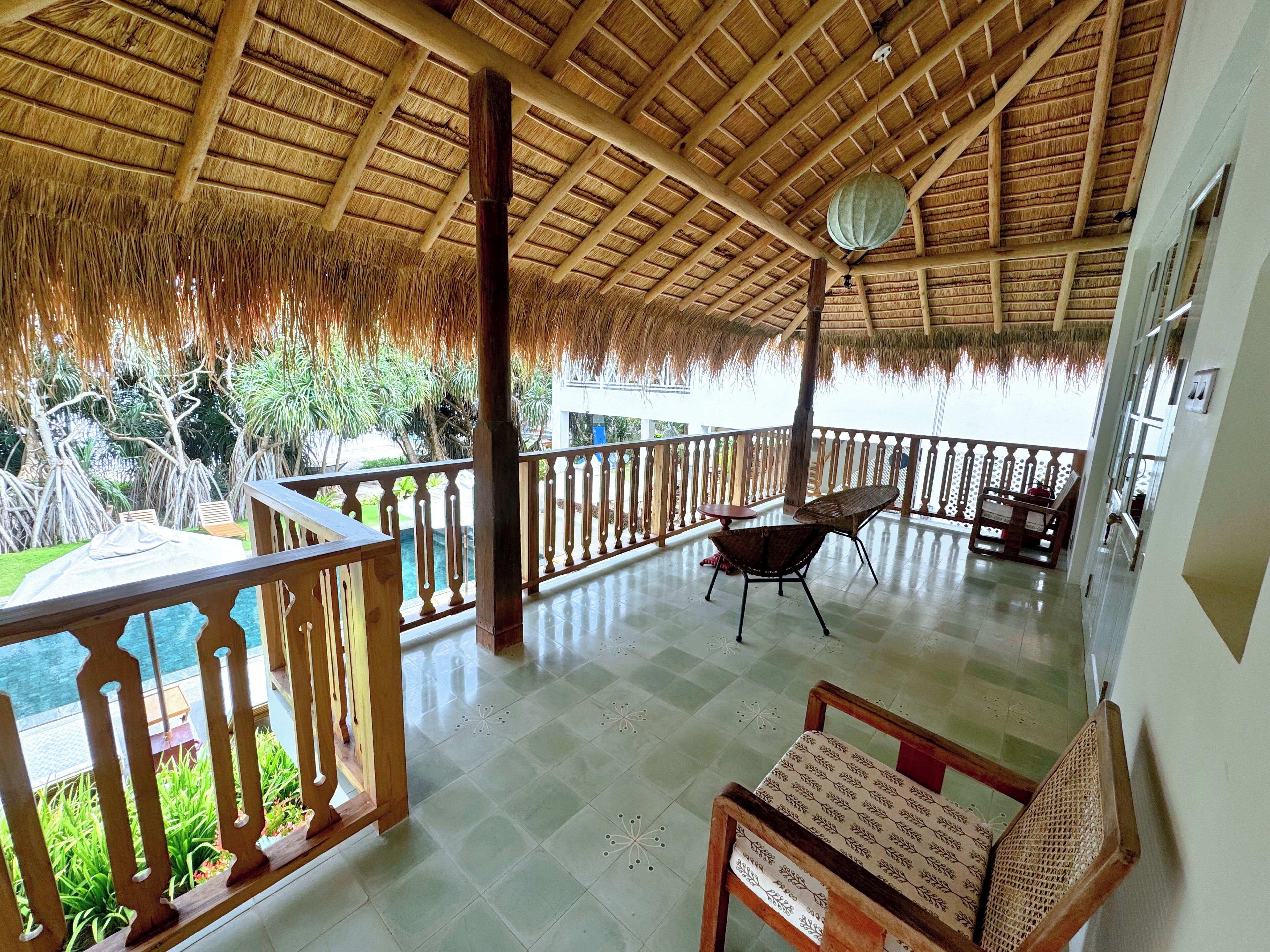 A covered outdoor area with a wooden railing, a table, and chairs.