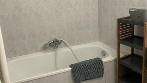 A bathroom with a bathtub, a towel rack, and a wooden shelf unit. - Lakefront apartment and walks (Rives)