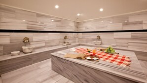 A modern bathroom with marble walls, a large bathtub, and a vanity with a red and white checkered towel. - Happy Inn Gebze Hotel (Gebze)