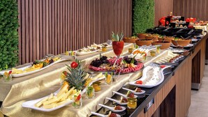 A buffet table with various food items and drinks, set against a wooden backdrop with a green wall. - Happy Inn Gebze Hotel (Gebze)