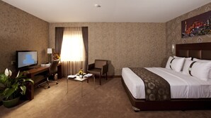 A hotel room with a bed, a desk with a TV, a chair, a coffee table, and a window with curtains. - Happy Inn Gebze Hotel (Gebze)