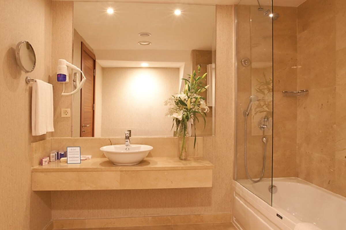 A bathroom with a sink, mirror, and shower.