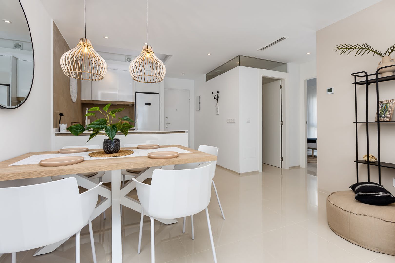 A modern kitchen with white cabinetry, a wooden dining table, and pendant lights.