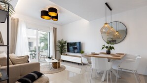 Un salon moderne avec un canapé, un pouf et un coin repas comprenant une table et des chaises en bois.