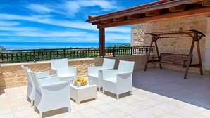 Una terrazza con mobili in vimini bianco, una ciotola di frutta e un'amaca.