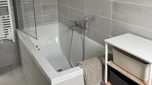 Un bany modern amb una banyera autònoma, un espai de dutxa amb envàs de vidre i cistos de vímet integrats als prestatges.