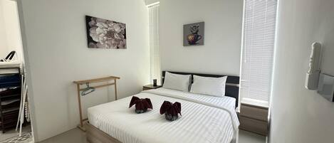 A modern bedroom with a large bed, a wooden bedside table, and two wall-mounted artworks.