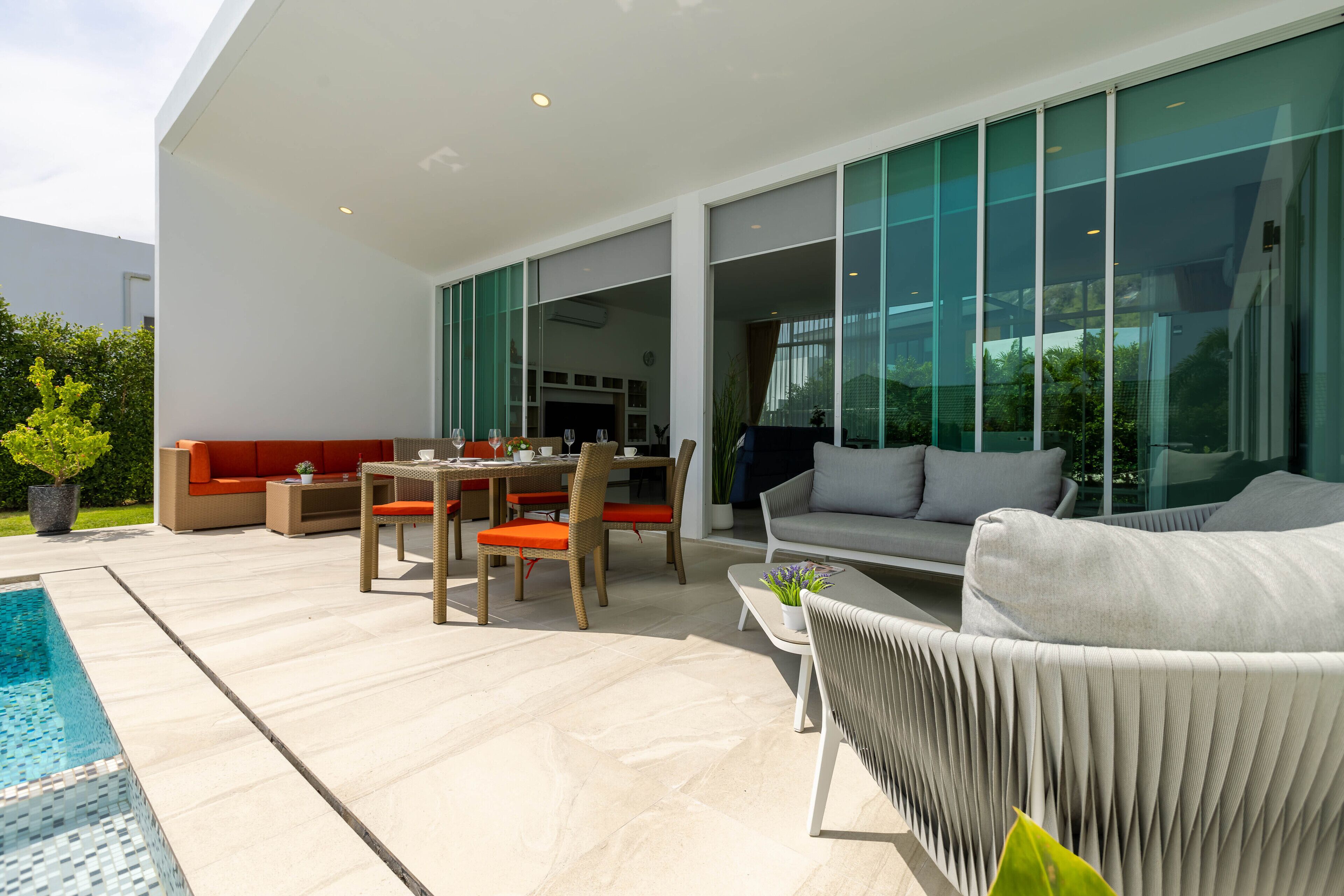 Uma área de estar moderna ao ar livre, com piscina, assentos e grandes janelas.