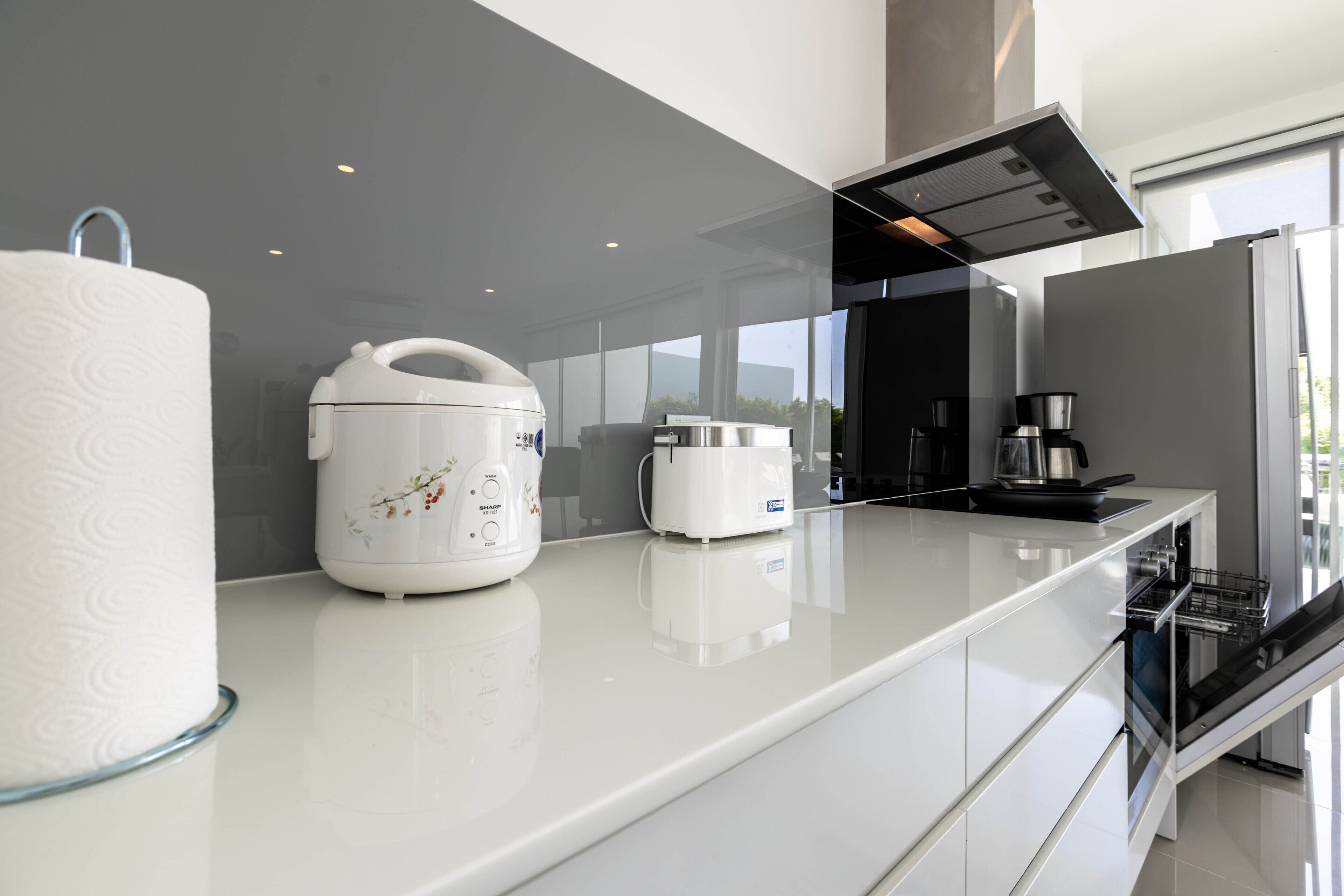 Una cocina moderna con encimera blanca, un cocedor de arroz, un tostador y una cafetera.