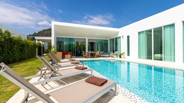 A modern poolside area with lounge chairs and a clear blue pool.