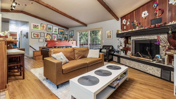 Una sala de estar acogedora con chimenea, vigas de madera, un sofá de cuero marrón y un comedor con mesa y sillas de madera.