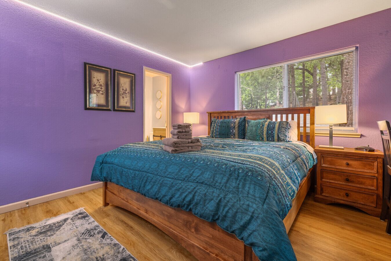 Une chambre à coucher avec un lit, une table de chevet, une fenêtre avec des stores et une porte.