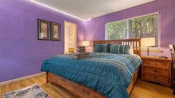 Une chambre à coucher avec un lit, une table de chevet, une fenêtre avec des stores et une porte.