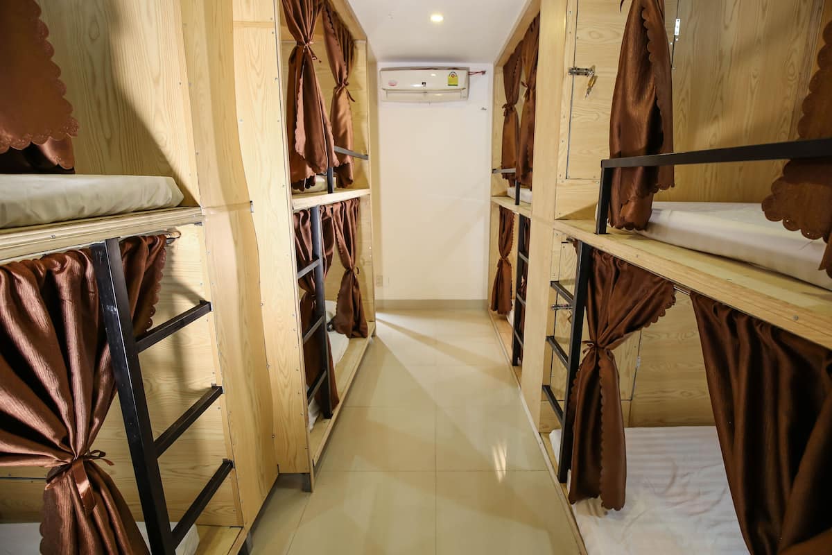 A corridor with bunk beds, wooden walls, and curtains.