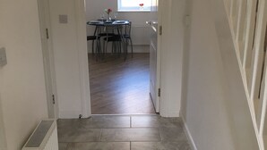 A hallway leading to a dining area with a table set for two, a radiator, and a window with a view. - The Central Lodge II (Dartford)