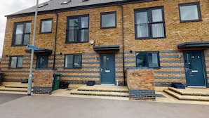 A multi-story brick building with uniform windows and doors, a visible street sign, and a clear sidewalk. - The Central Lodge II (Dartford)