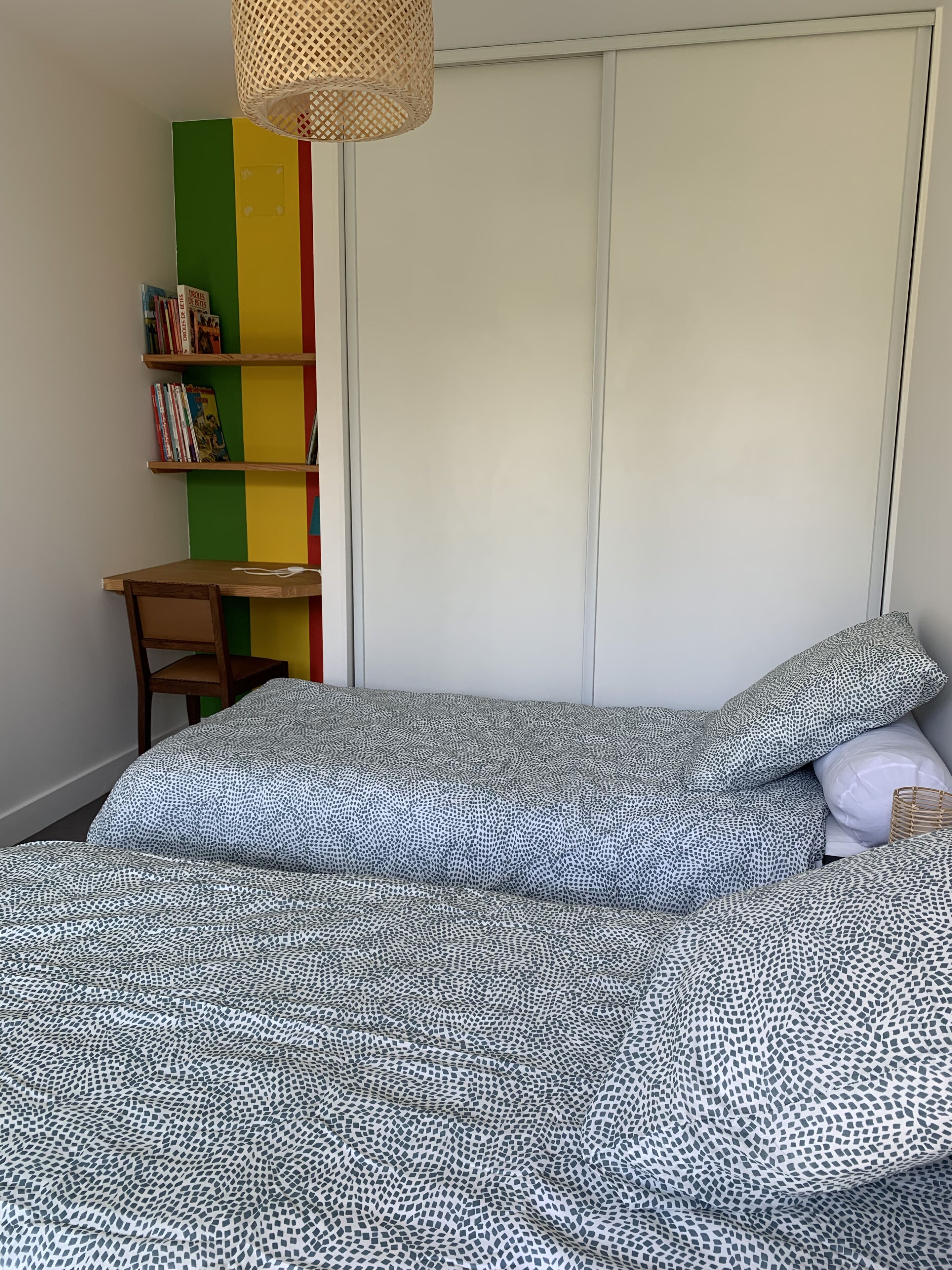 A bedroom with a bed, a chair, a bookshelf, and a wardrobe.