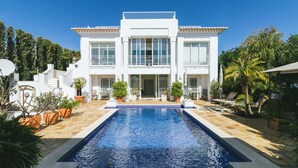 Un bâtiment blanc à deux étages, avec une piscine devant.